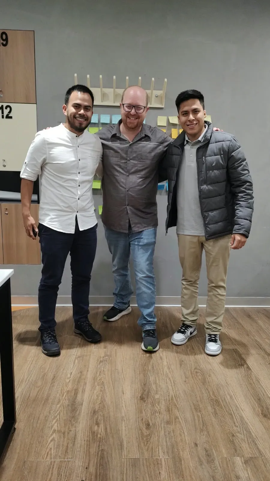 Gabriel con Javier y Fabrizio, del equipo de Núcleo Lab, frente a una pared con post-its